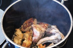 Fleischknochen im oel fuer Roestaromen anbraten - die frau am grill
