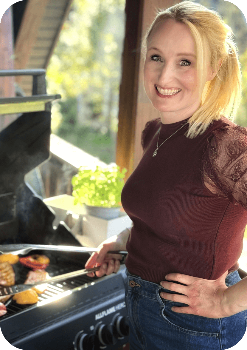 Anja steht am Grill und lächelt in die Kamera