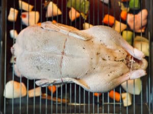 ente liegt auf backrost ueber backblech im backofen