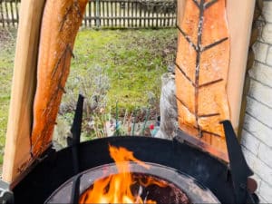flammlachsbretter mit lachs an feuertonne montiert