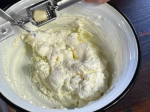 frischkaese, creme fraiche, oliven, oregano und gepresster knoblauch in schuessel verruehrt