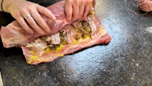 fuehstuecksspeck ueber den aufgeschnittenen spiessbraten verteilen und eng zusammen rollen