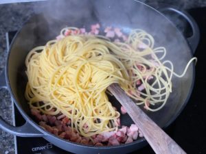 gekochte spagehtti zum heissen ausgelassenen speck in pfanne geben