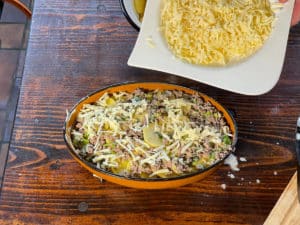 geriebenen kaese ueber kartoffelauflauf streuen