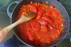 geschaelte tomaten in shakshuka pfanne andruecken