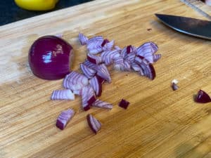 geschaelte und klein geschnittene zwiebel auf einem brett