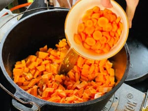 geschnittene karotten in suesskartoffel suppe geben