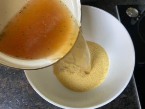 heisse gemuesebruehe zum couscous in die schuessel giessen