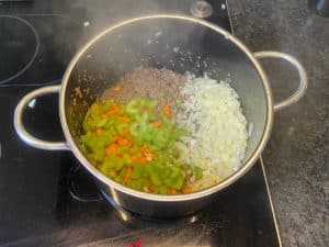karotten, zwiebeln, knoblauch und staudensellerie zum angebratenen hackfleisch geben