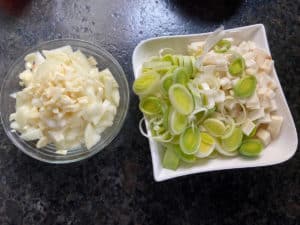 knoblauch, zwiebel, lauch und sellerie klein geschnitten in tellern