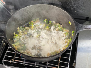 lauch, zwiebeln und knoblauch in pfanne mehlieren