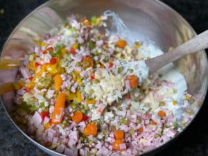 moehren, kaese, schinken und essiggurken in nudelsalat dressing geben