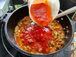 passierte und stueckige tomaten in die pizzasuppe geben