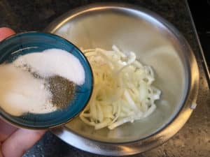 rohe zwiebelringe mit salz, pfeffer und zucker wuerzen