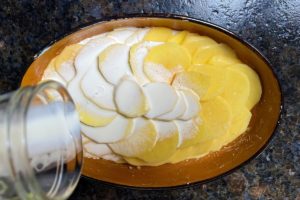 sahne ueber die geschichteten kartoffeln in die auflaufform geben