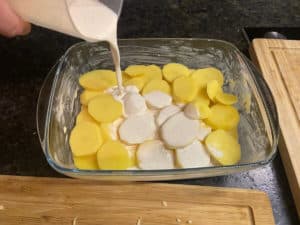 sahne ueber geschichtete kartoffelscheiben in backform giessen