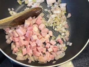 schinkenwuerfel zu angeduensteten zwiebeln in die pfanne geben