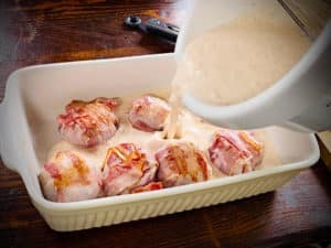 schweinemedaillons im speckmantel mit sauce in auflaufform geben