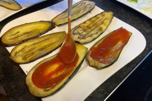 vorgegarte auberginen scheiben mit tomaten sosse einstreichen