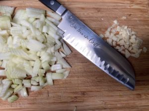 zwiebeln in wuerfel geschnitten und gehackter knoblauch auf einem brett