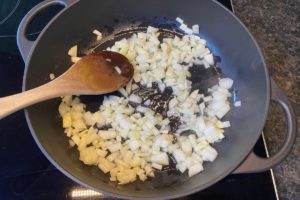 zwiebeln und knoblauch fuer den djuvec reis in einer pfanne im heissen oel anschwitzen