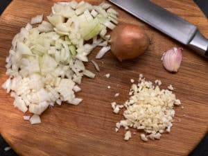zwiebeln und knoblauch klein geschnitten auf brett