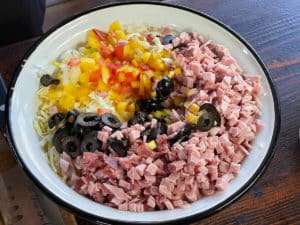 zwiebelwuerfel, gehackte tomaten, geriebner gouda, olivenringe, schinkenwuerfel und salamiwuerfel in frischkaesemischung mischen